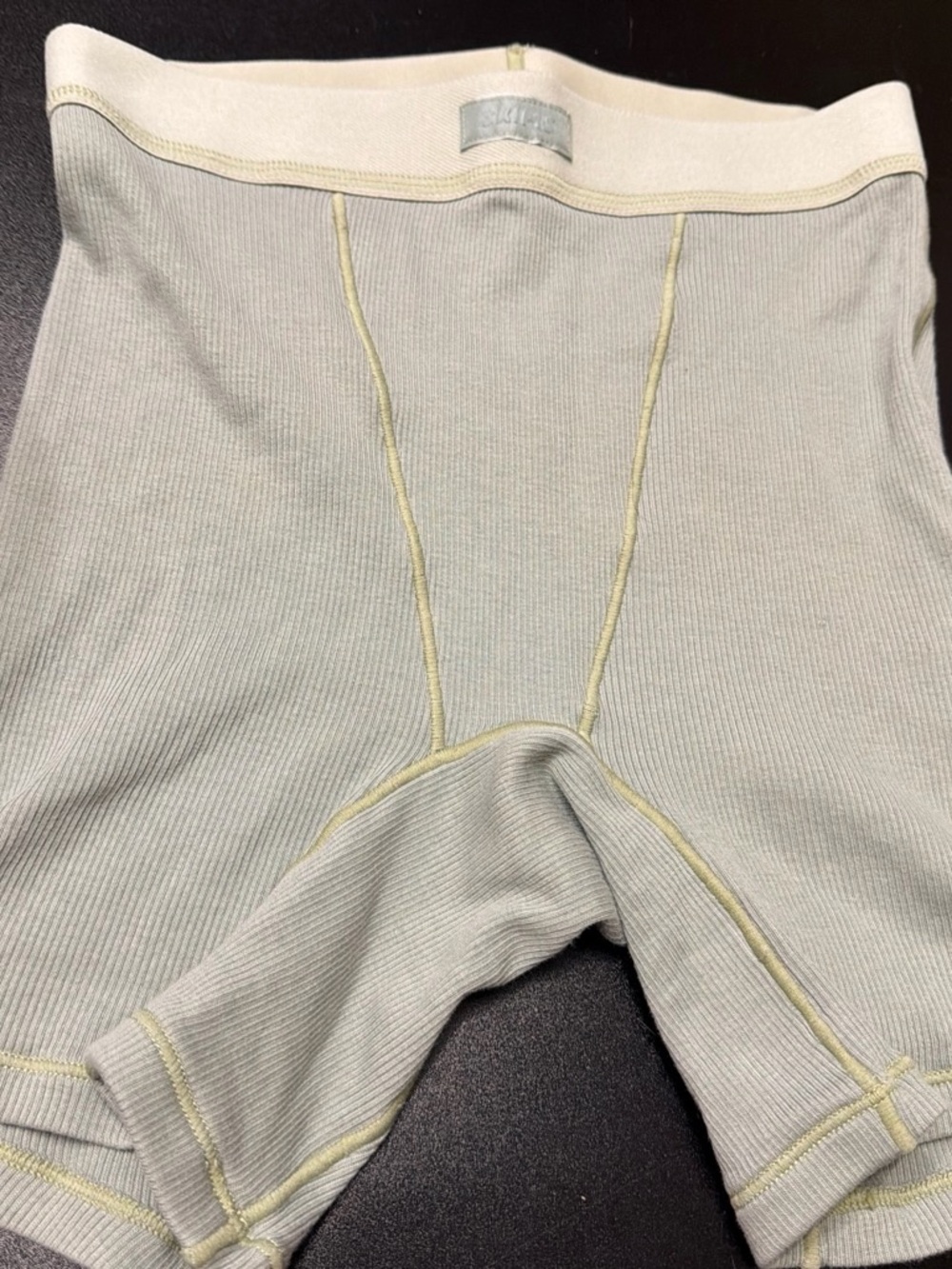 SKIMS Light Gray Ribbed Bike Shorts with Cream Waistband and Yellow Stitching